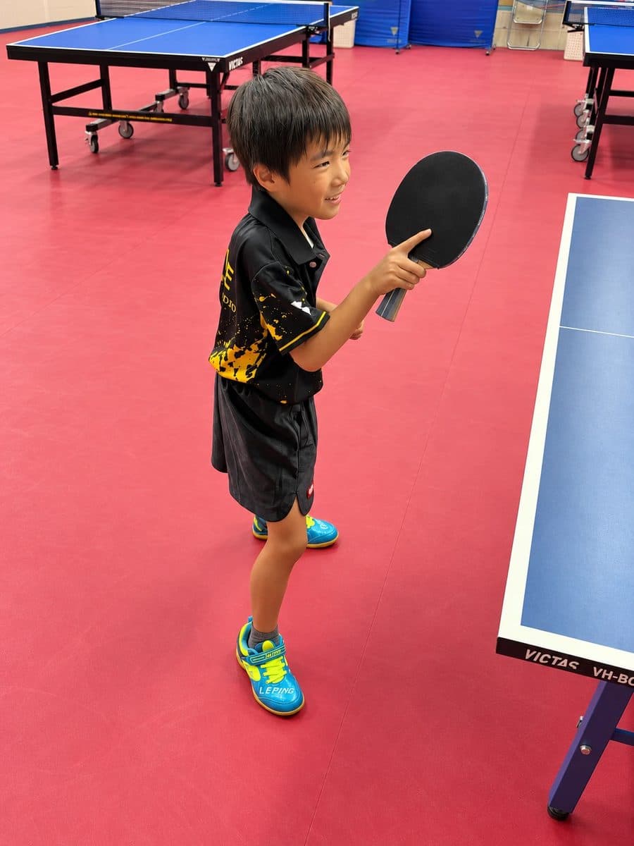 ラケットを構えて笑顔を見せる小学生